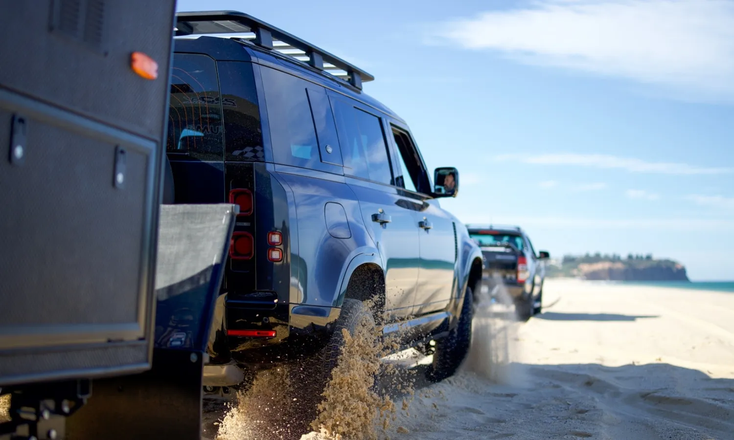 Caravan being towed on beach sand by 4WD vehicle