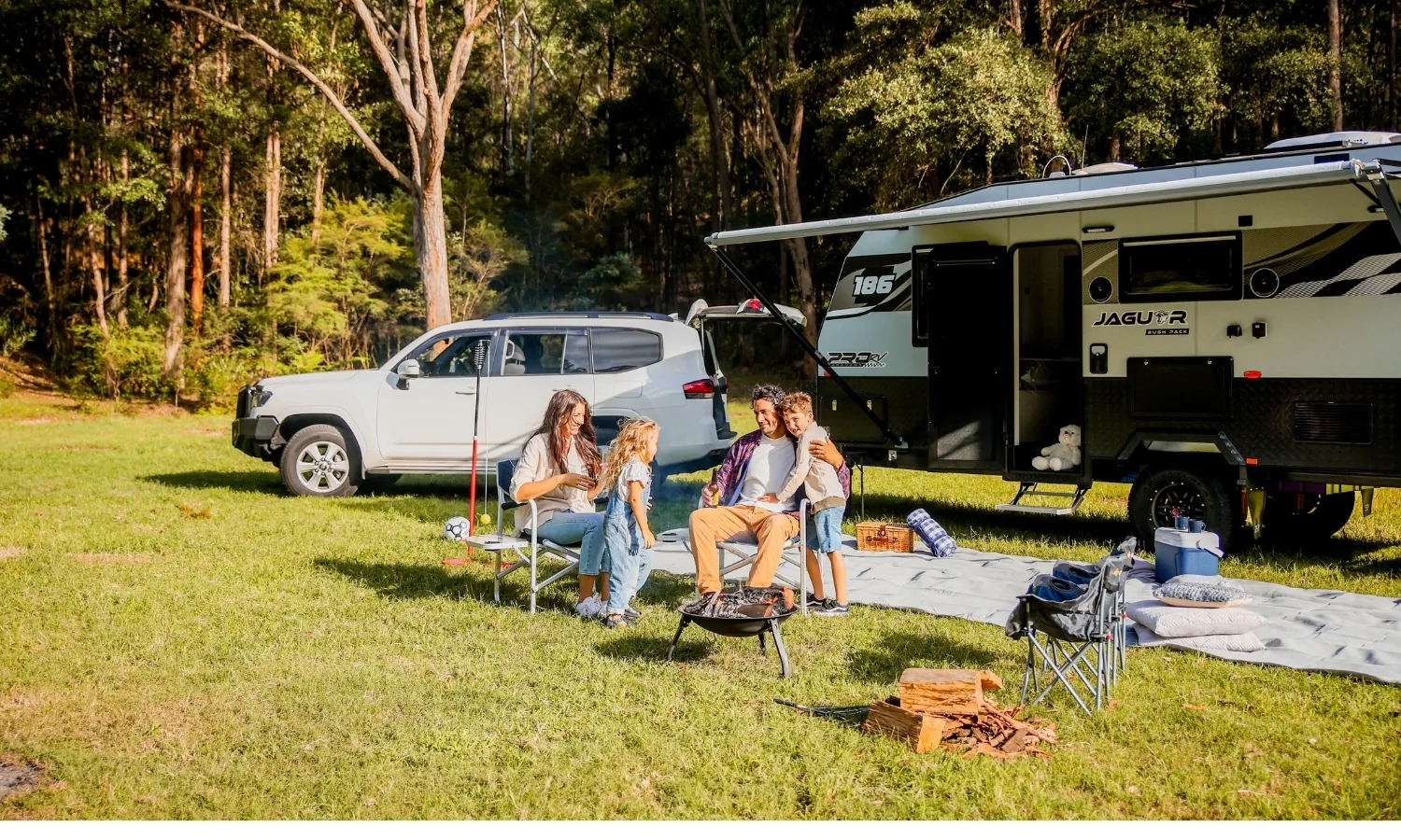 Family caravan camping setup with outdoor chairs and awning extended