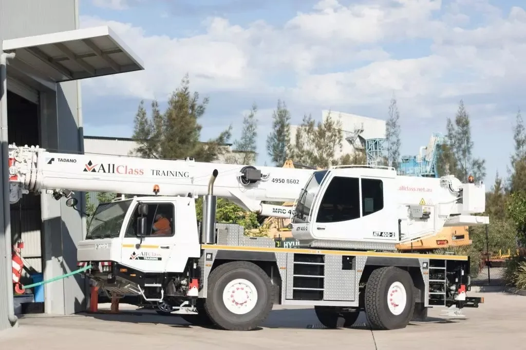 An All Class Training mobile crane parked outside the workshop