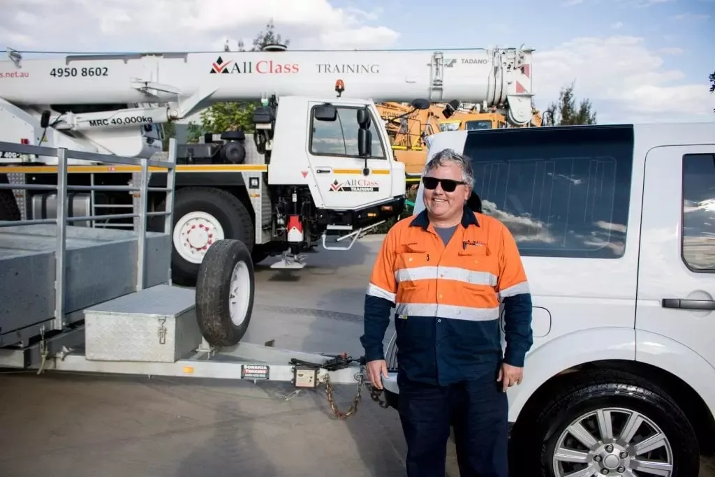 An All Class Training instructor standing between a tow vehicle and a plant trailer