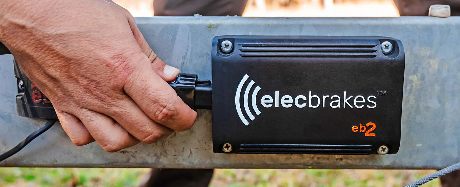 A technician installing an Elecbrakes electric braking system on a vehicle. The image shows a close-up of the installation process.