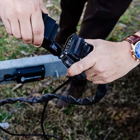 A close-up shot of an electrician installing an Elecbrakes electric braking system. The image shows hands carefully connecting wires to a component.