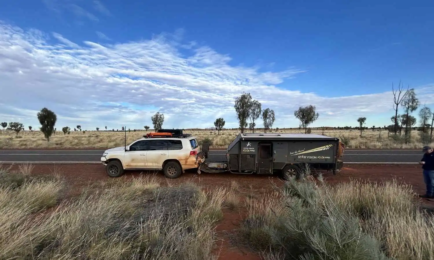 Rear view of a caravan parked on a roadside with open landscape ahead