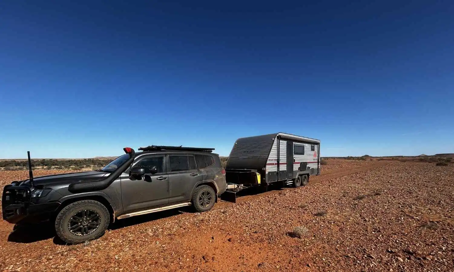 Car and caravan setup on a red dirt road in the Australian outback