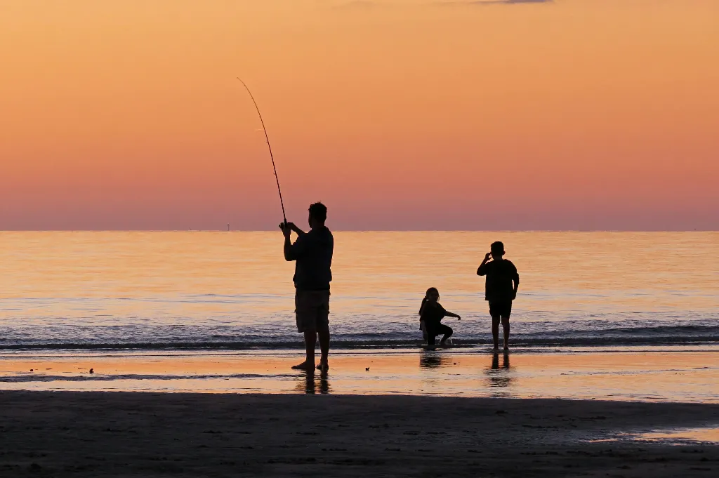 Father and two children fishing at sunset at Burrum Heads