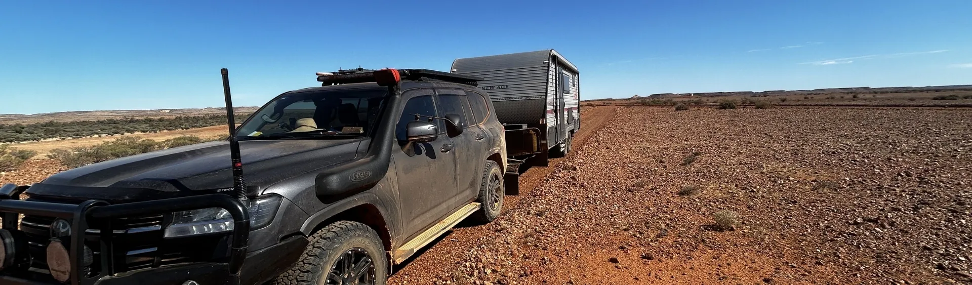 Tow vehicle and off-road caravan travelling downhill through the Australian outback