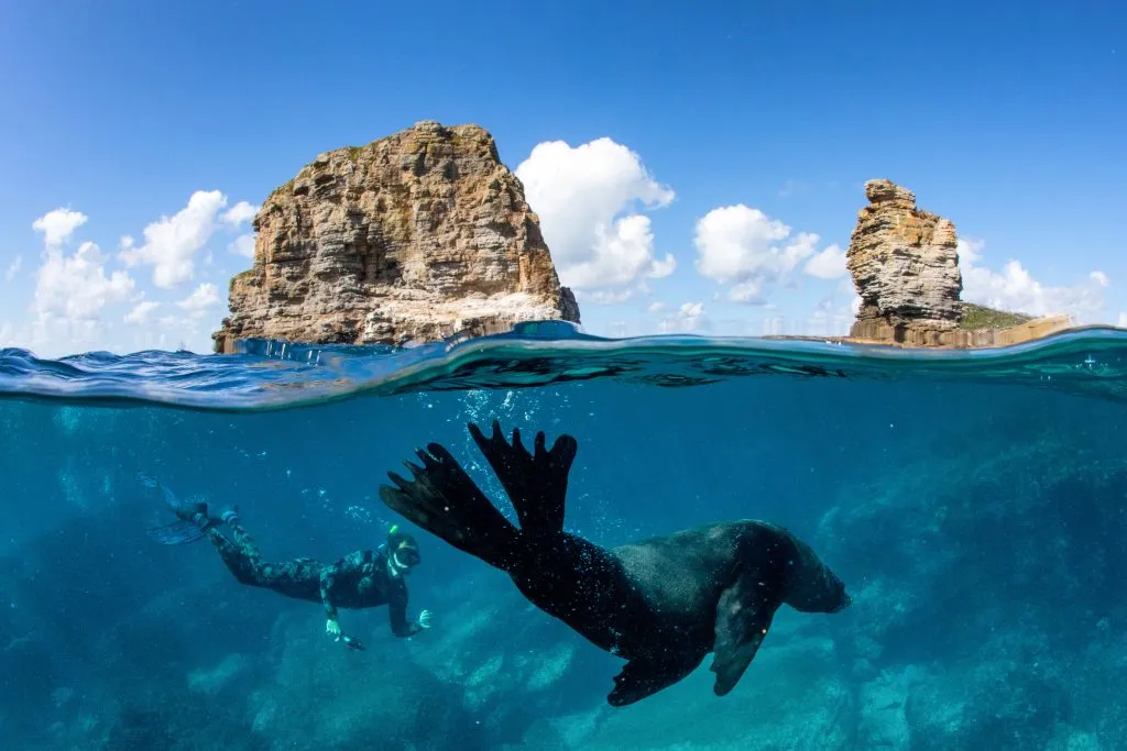 Stunning panoramic view of Jervis Bay, Australia, featuring calm turquoise water and a bright sunrise.