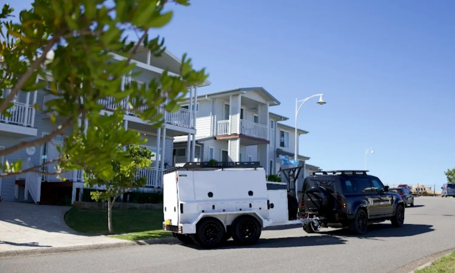 White work trailer hitched to a ute on a suburban street