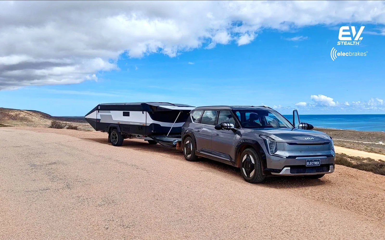 A sleek, silver Kia EV9 electric SUV is shown in a three-quarter view, parked outdoors against a blurred background. The focus is on the vehicle's design and profile.