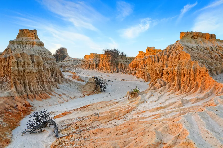 Eroded sand formations under a blue sky.