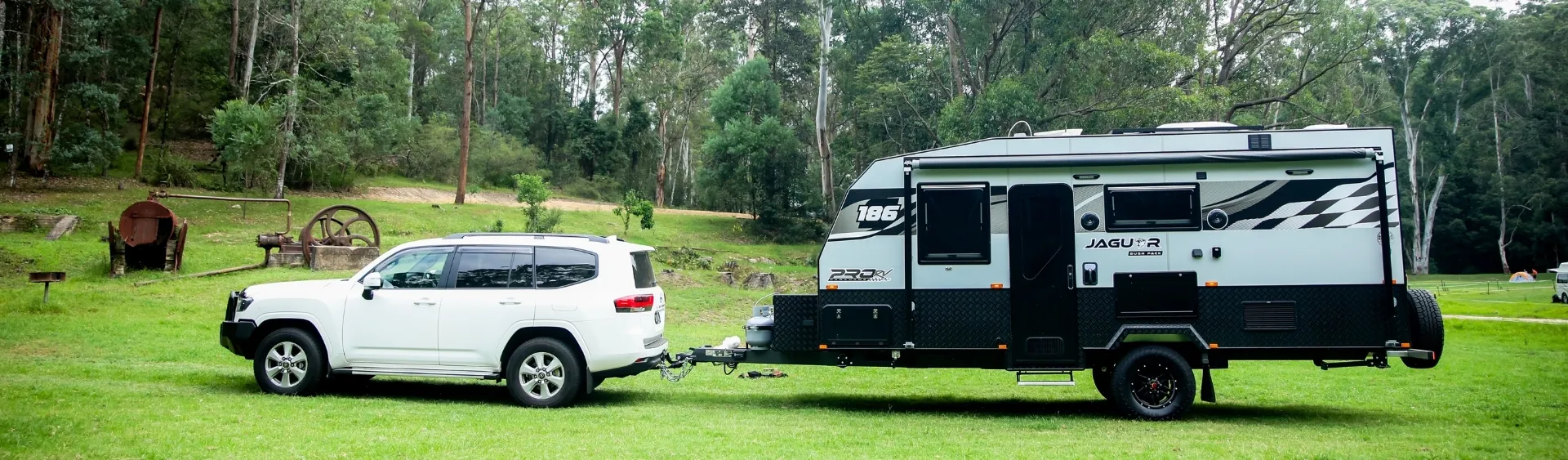 Caravan being towed across wet green grass in open landscape during daytime