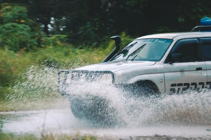 A 4WD driving through a puddle on a wet road