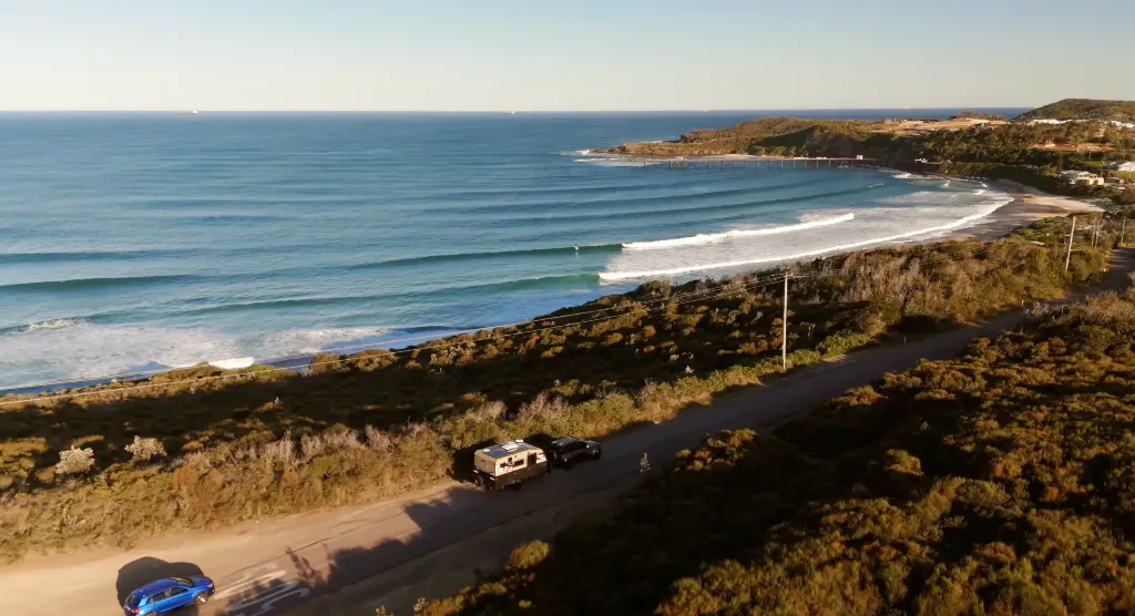 Car tows caravan along a coastal road