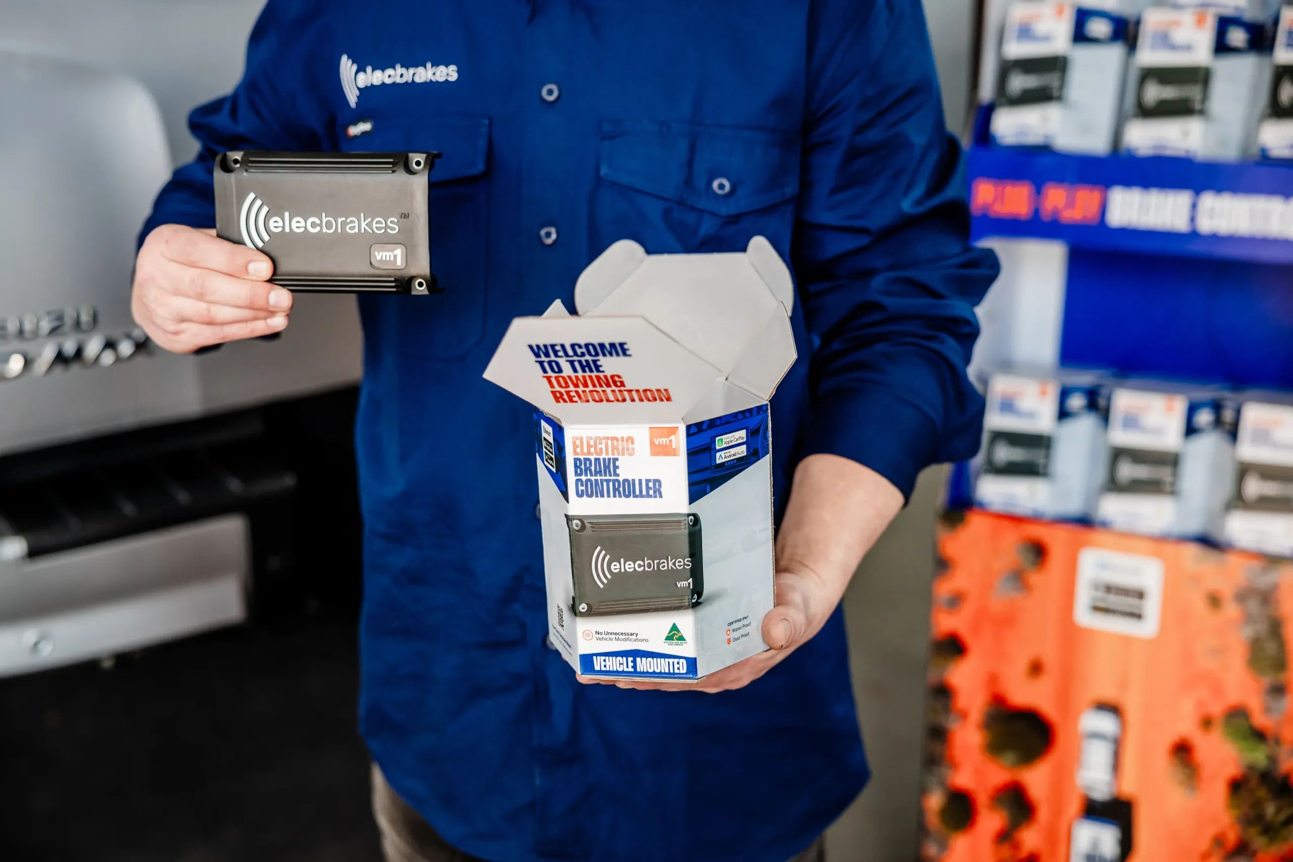 An Elecbrakes staff member holding a VM1 brake controller beside its open retail box